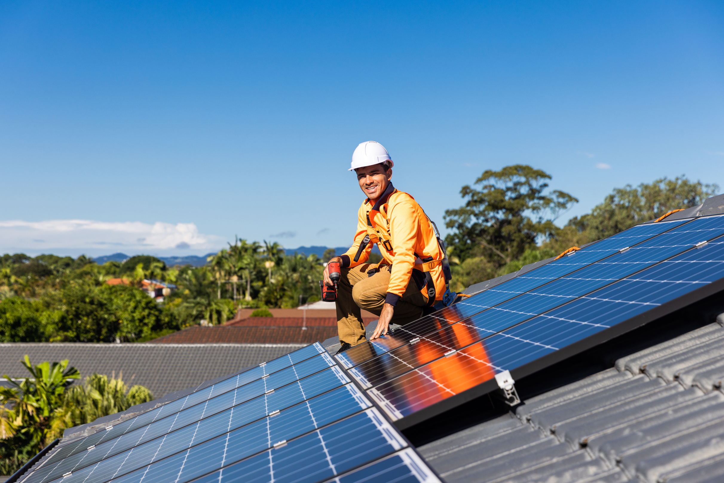 Solar panel technician with drill installing solar panels